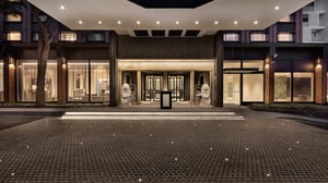 Elegant Accor Pullman Auckland hotel entrance at night with illuminated steps, large glass doors and stone lion statues at the entryway.