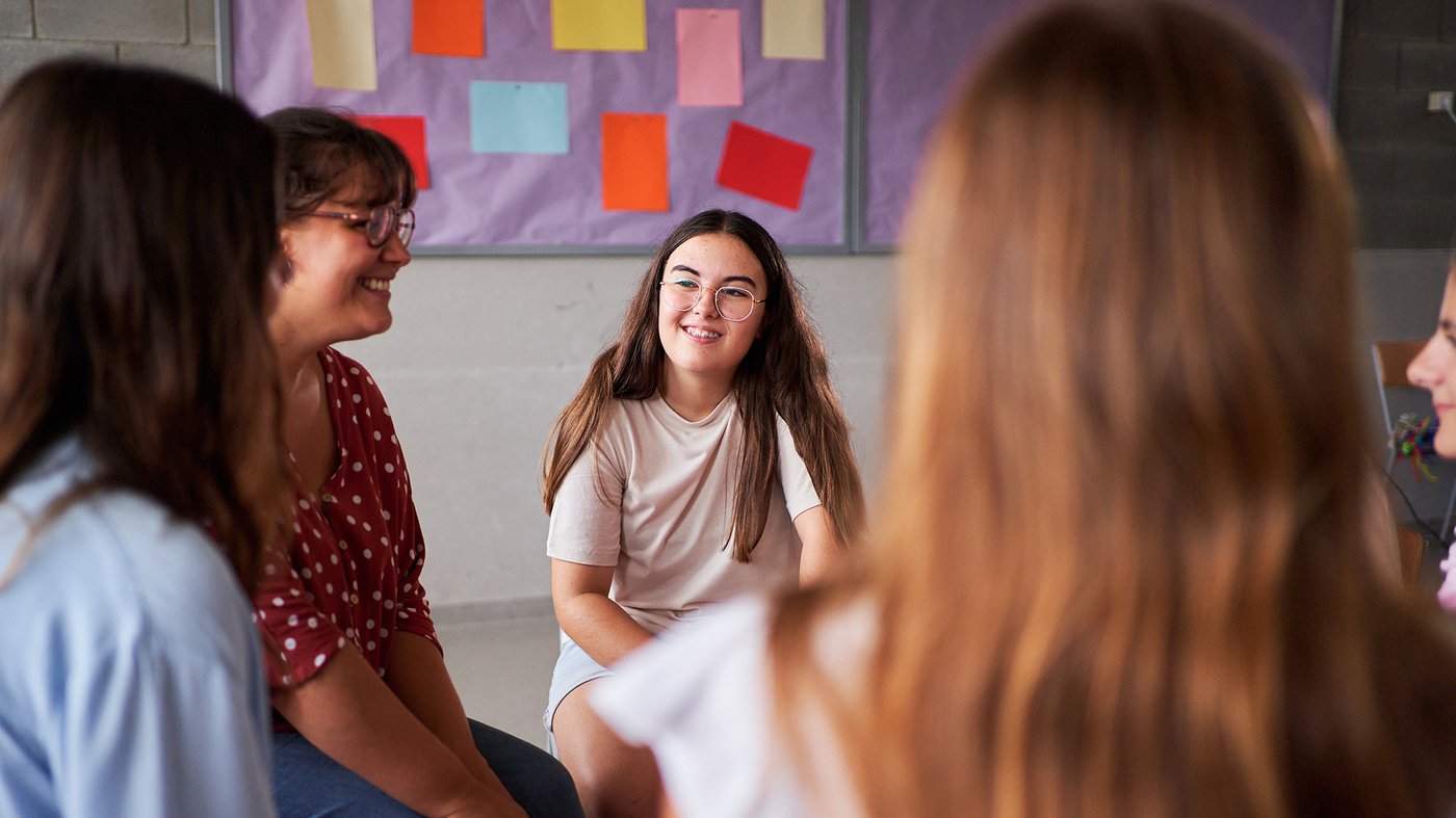 Young girl smiling while participating in a supportive community group discussion.