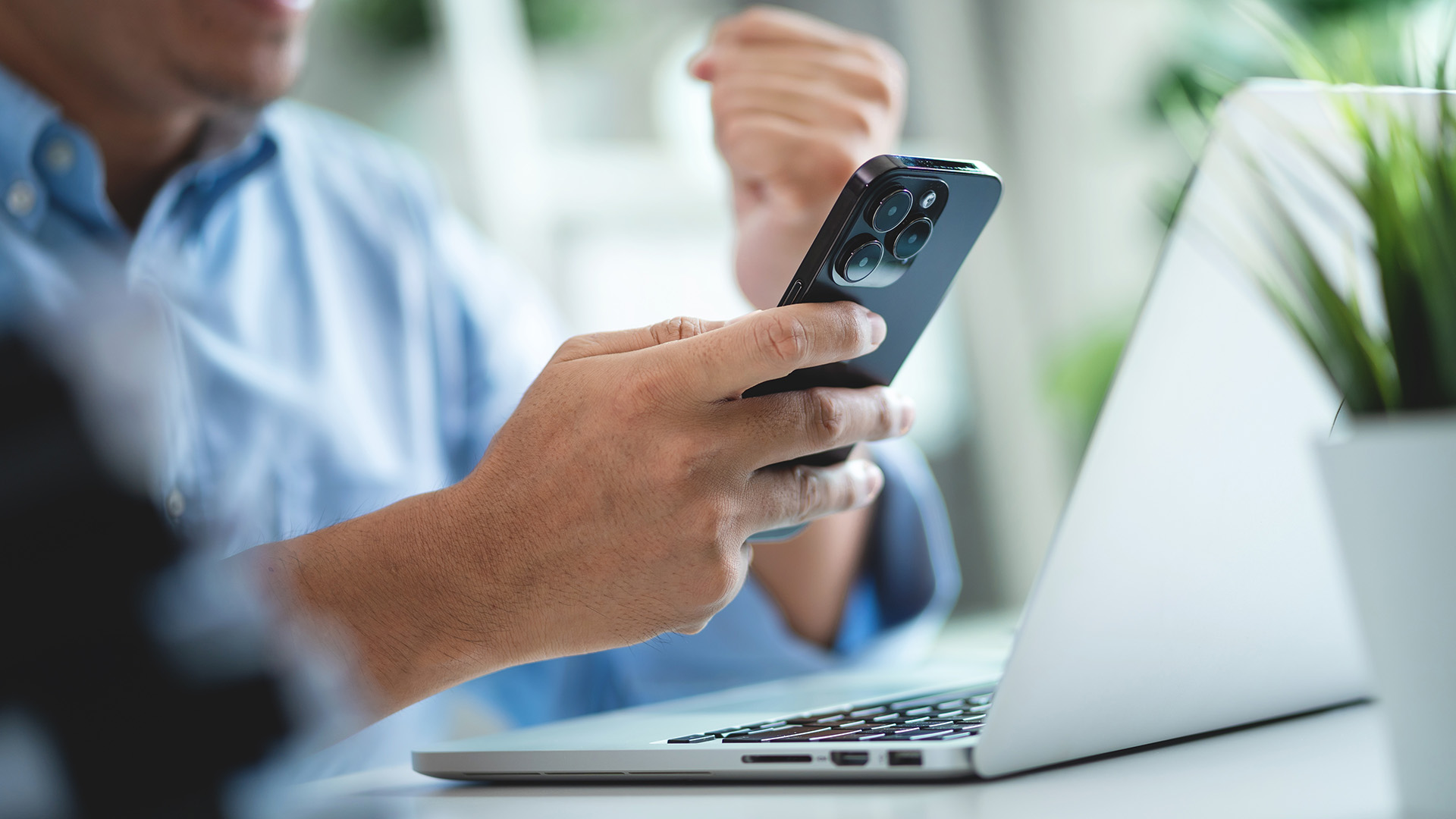 Person using a smartphone next to a laptop, illustrating mobile printing and cloud connectivity for business.