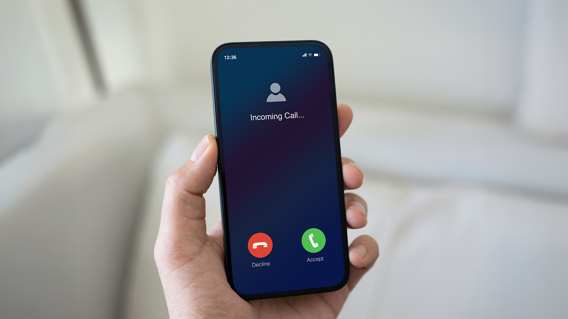 A hand holds a smartphone showing an incoming call screen with options to decline or accept.