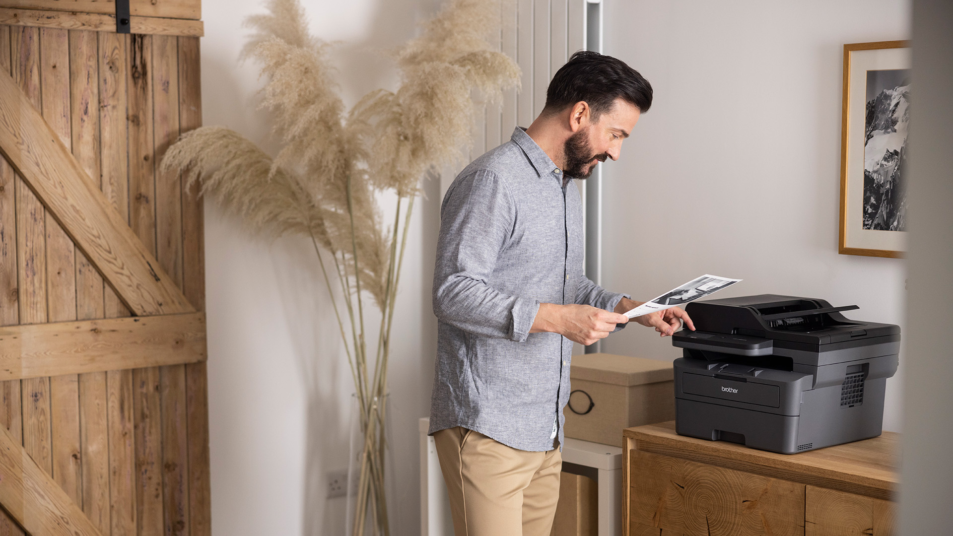 Man using a Brother multifunction printer in a home office.