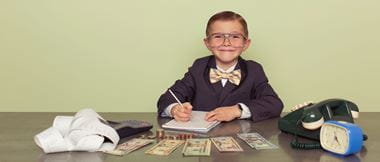 young boy businessman sits behind a desk