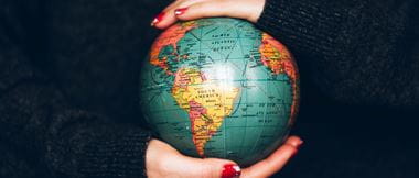 Woman's hands carefully holding a small globe, highlighting environmental responsibility