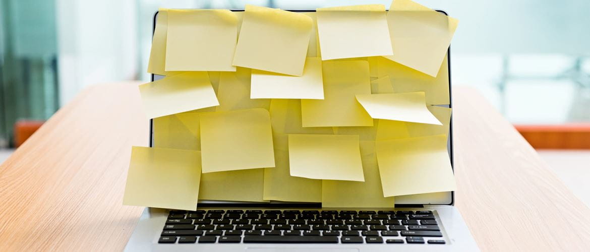 A laptop screen covered in yellow post-it notes