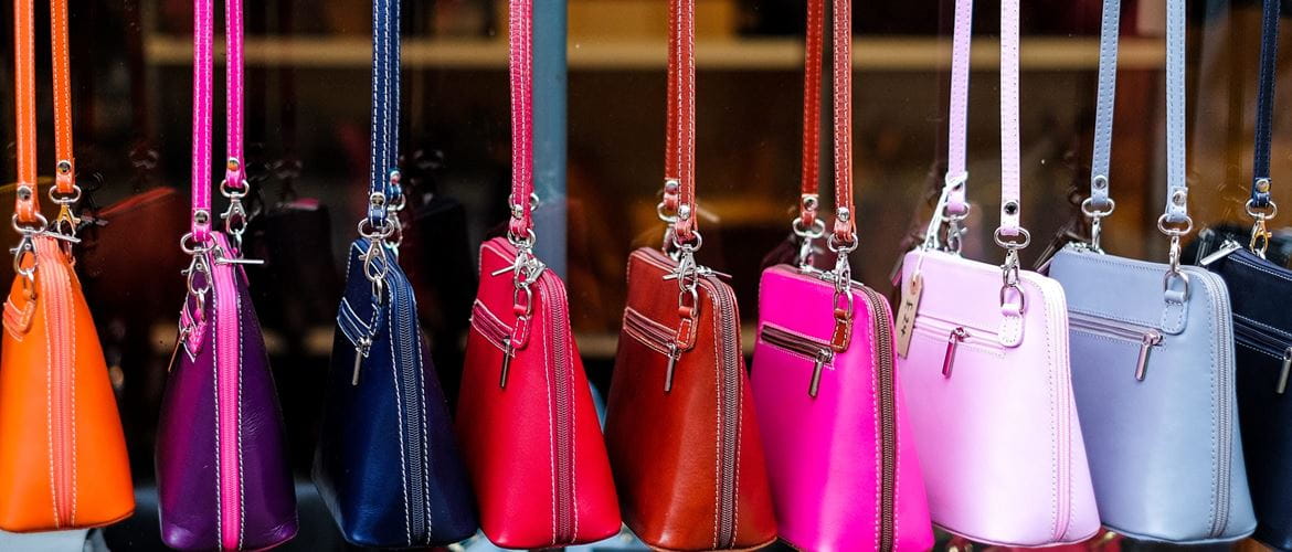 a row of colourful leather handbags for sale