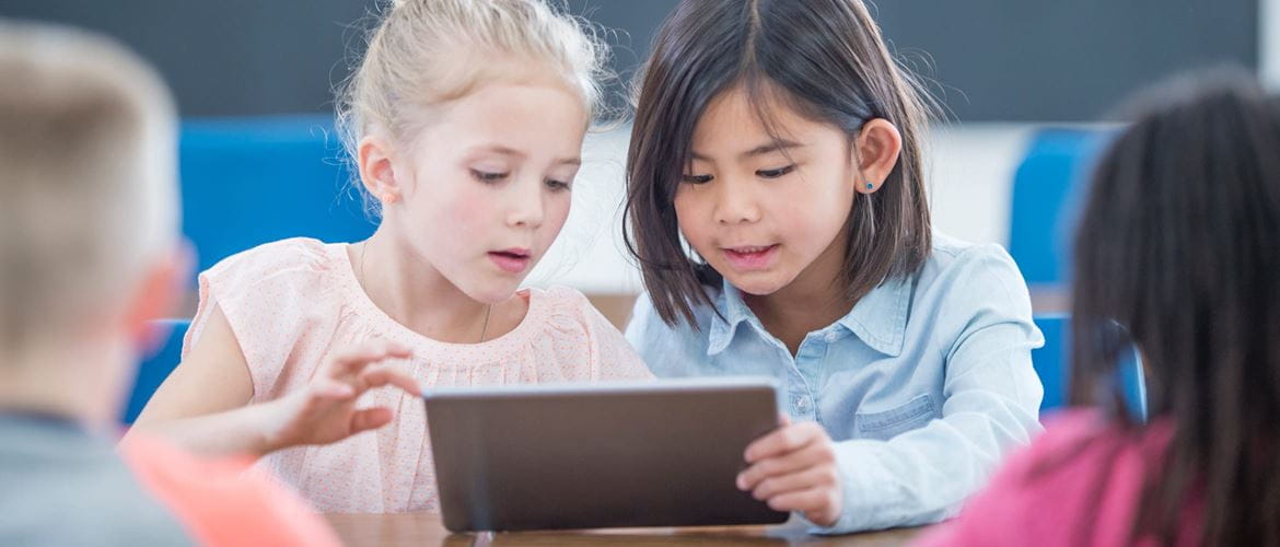 young children using a tablet in a classroom setting