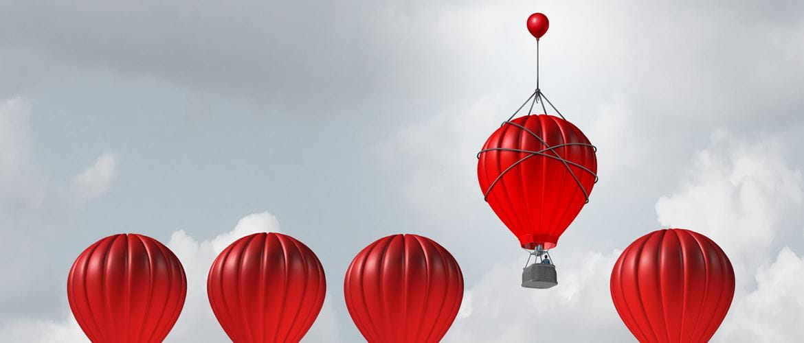 one red hot air balloons flying higher than four other identical balloons