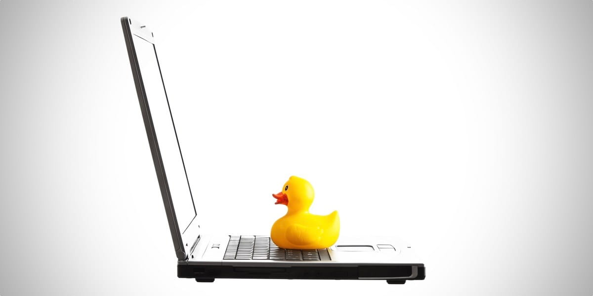 yellow rubber duck sat on a laptop