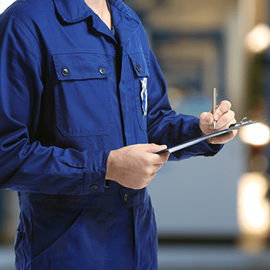 Technician in blue uniform holding a clipboard and pen, representing managed printing services by Brother.
