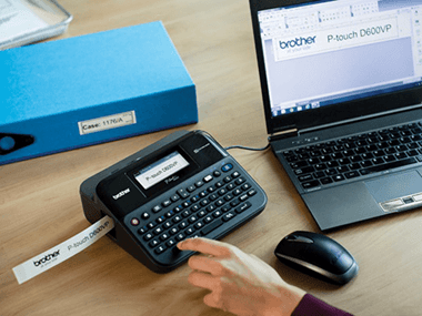 A persons hand using a Brother P-touch label printer to print using Brother Genuine Consumables