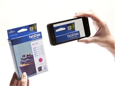 A hand using a mobile phone app to scan a Brother consumable ink to check if it's genuine