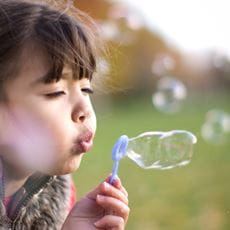 young girl blowing bubbles in a field brother